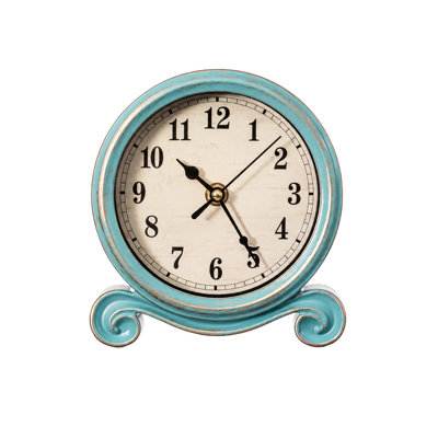 Horloge de table ronde vintage avec cadre bleu vieilli, base ornée de volutes et design d'inspiration antique, idéale pour être posée sur un foyer, un comptoir ou une étagère dans un salon, une chambre ou un bureau.