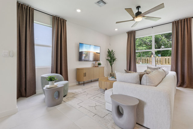 Living room with sand-colored furniture, curtains, and area rug.