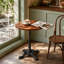 Table de bistro ronde vintage, plateau en pin massif, piètement en fonte à quatre pattes pointues, noire