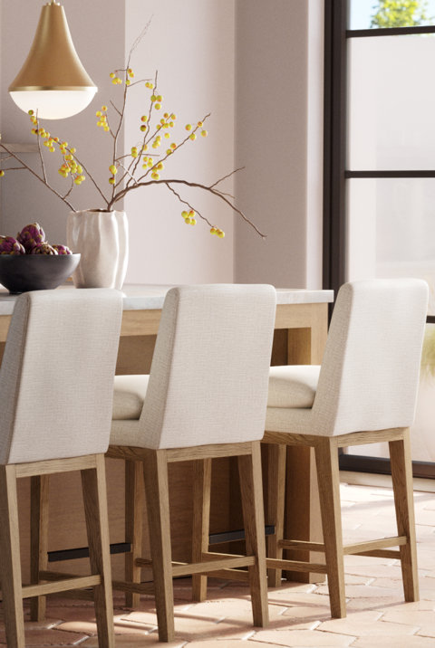 Three upholstered bar stools at a kitchen island