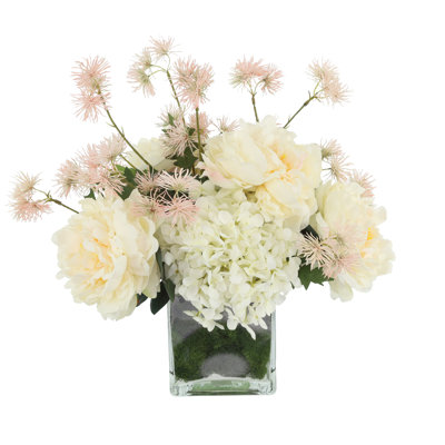 Arrangement d'hortensias, de pivoines et de chardons dans un vase en verre