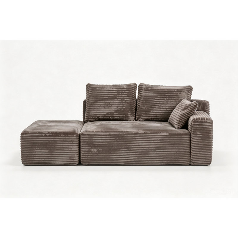 Petit canapé d'angle modulaire Cloud avec assise profonde, pouf et 3 coussins, en velours côtelé marron, méridienne à droite.