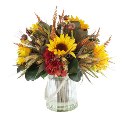Arrangement d'automne tournesol, hortensia et grenade dans un vase en verre