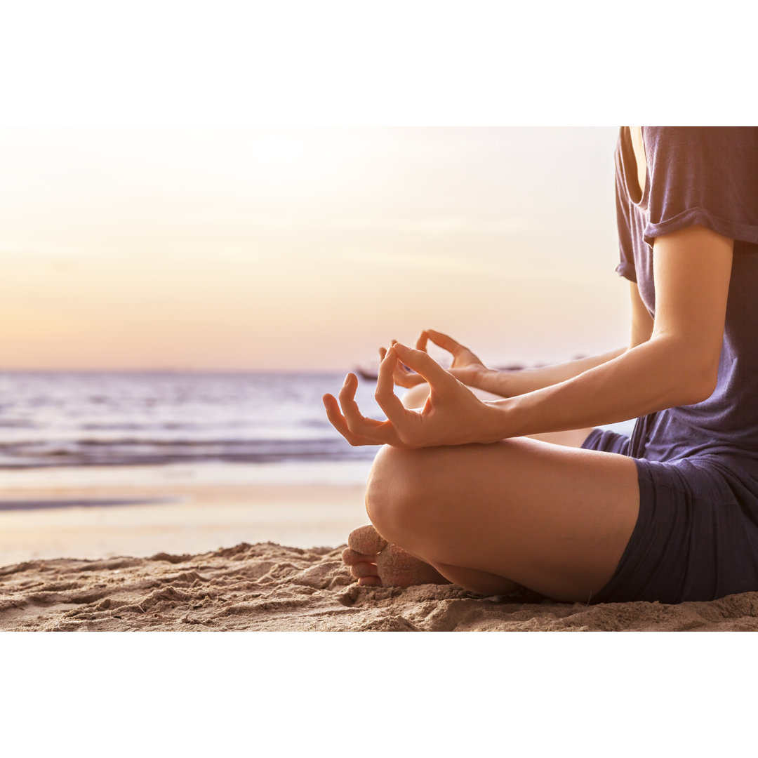 Leinwandbild Junge Frau praktiziert Yoga am Strand für Harmonie