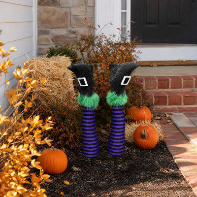 Piquets de jardin en forme de jambes de sorcière pour l'Halloween (lot de 2), avec chaussures de sorcière pailletées et bas rayés violets et noirs. Décorations de jardin pour Halloween.