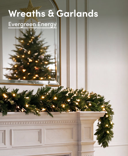 Wreaths & Garlands Evergreen Energy, featuring a pre-lit Christmas garland draped over a mantel with a reflection of a decorated Christmas tree in a mirror.