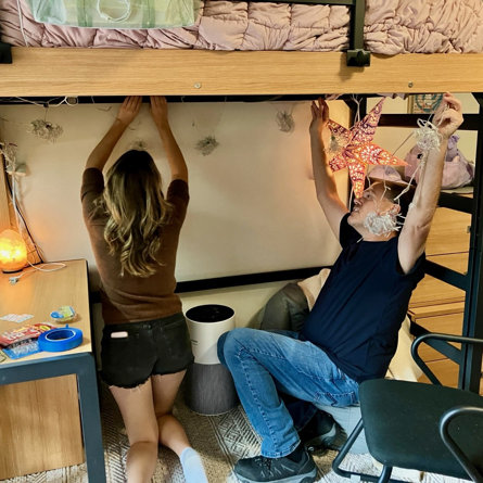 Anthony Martorina helps daughter Siena hang strand lighting in her dorm room.