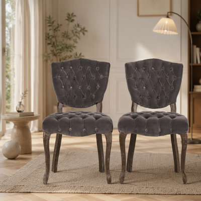 Ensemble de deux chaises capitonnées d'inspiration européenne avec pieds sculptés à la main et revêtement capitonné pour des solutions d'assise polyvalentes.