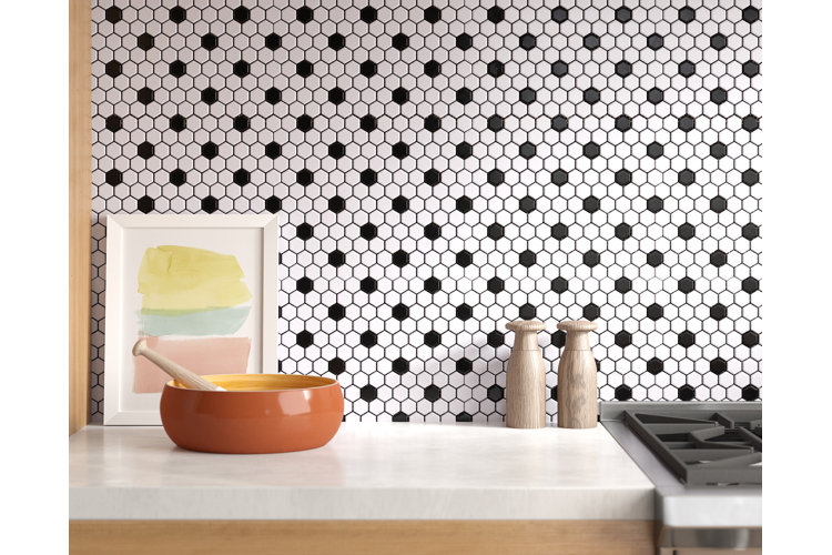 Black and white hexagonal mosaic tile backsplash in a kitchen. White counter with a ceramic mortar and pestle and two wood salt and pepper mills