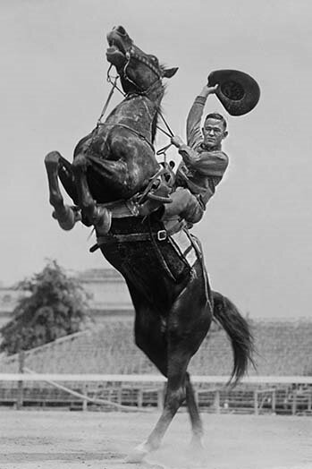 Buyenlarge Cowboy Rides Rearing Horse and Waves His Hat - Photograph Print