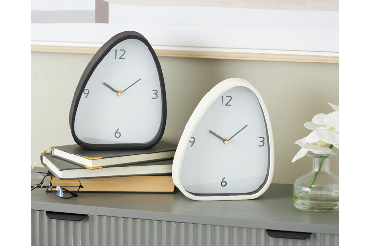 One black and one white alarm clock on a pile of books. Flowers in a glass vase