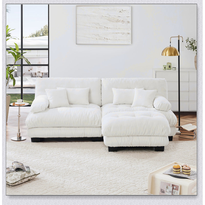 Luxueux canapé en chenille pour le salon avec plusieurs coussins et repose-pieds convertible, pour plus de confort et de style.