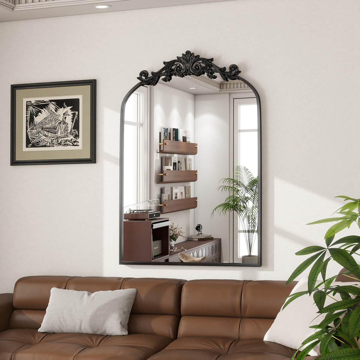 Black baroque mirror with ornate crest mounted above a brown leather couch in a modern living room