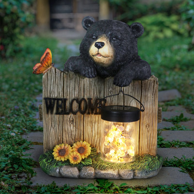 Exhart Solar Hand Painted Bear Garden Statue with a Lantern Jar of LED Bumblebees by a Welcome Fence