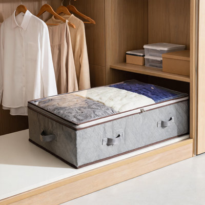 Ensemble de 4 sacs de rangement pliables en tissu gris (90 L) à glisser sous le lit. Fermeture à glissière, fenêtre transparente et poignées renforcées. Parfait pour les vêtements, la literie et les oreillers. Dimensions : 100 x 50 x 18 cm.