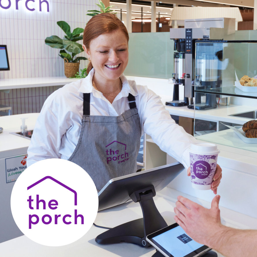 The Porch employee handing customer coffee.