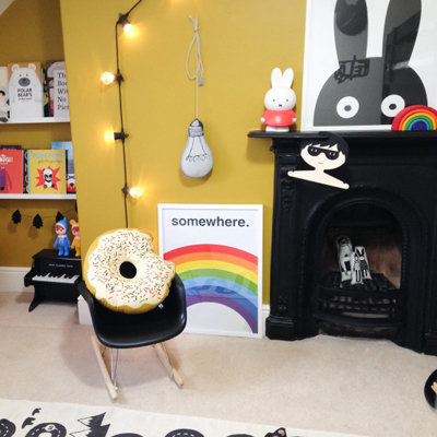 a colourful bedroom with mini Eames chair, fireplace, and giant bunny print