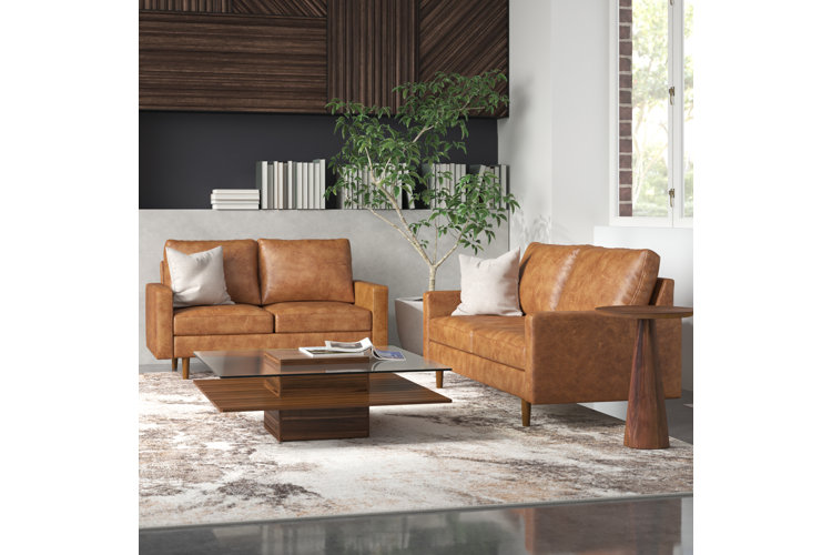 modern living room with two brown leather sofas, beige and brown rug, and glass coffee table