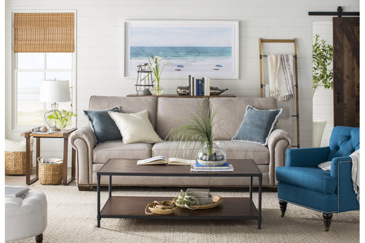 A light wood and metal blanket ladder with blankets on it in a coastal style living room.