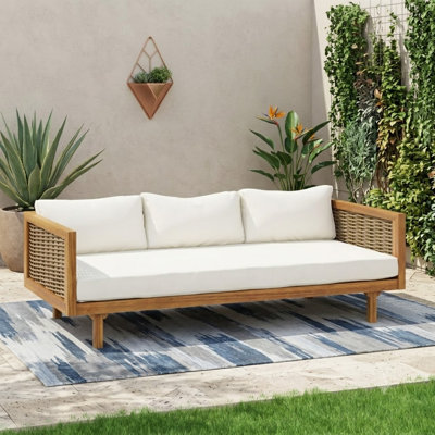 Lit de jour à trois places équipé d'accoudoirs en rotin et d'un coussin beige