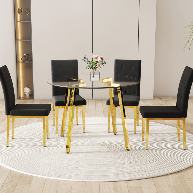 Table de salle à manger ronde en verre trempé transparent avec pieds en métal doré et 4 chaises en velours noir à dossier quadrillé, solution élégante visuellement époustouflante