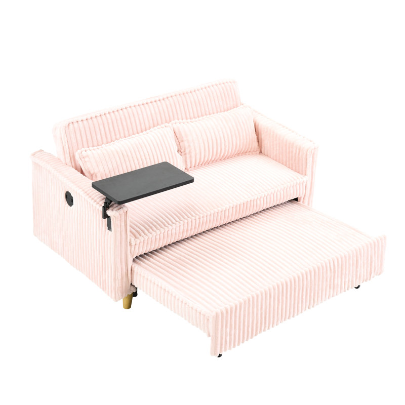 Velours côtelé rose avec des ajouts novateurs : lit gigogne, table basse amovible, ports pour une expérience inédite. Élégant : ports, se transforme en lit luxueux.