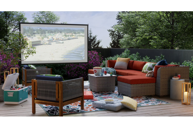 Large projector screen in a backyard with a large conversation patio set, outdoor rug, blue cooler, and plenty of sofa cushions