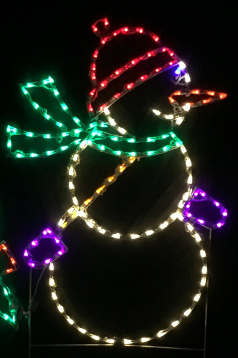 Multicolor LED lighted snowman yard decoration wearing a red hat, green scarf, and purple mittens against a black background.