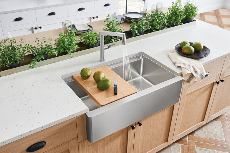 a wood cutting board with mangoes and a knife on it sitting over a sink
