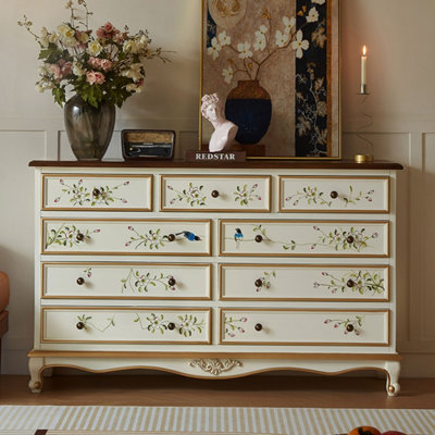 Meuble à neuf tiroirs en bois massif blanc crème, peint à la main avec un motif floral et d'oiseaux