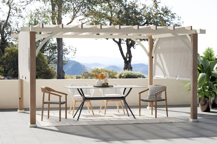 outdoor dining space with a wood pergola, modern dining set, and a tray full of tabletop decor