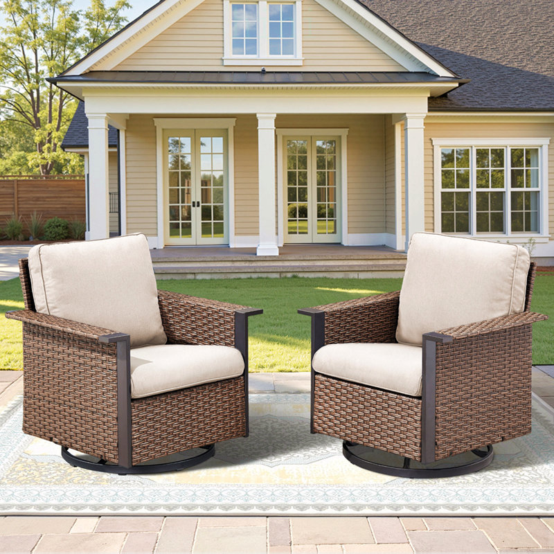 Ensemble de fauteuils à bascule pivotants d'extérieur en osier brun, avec larges accoudoirs et coussins beiges pour un confort optimal sur la terrasse et le patio.