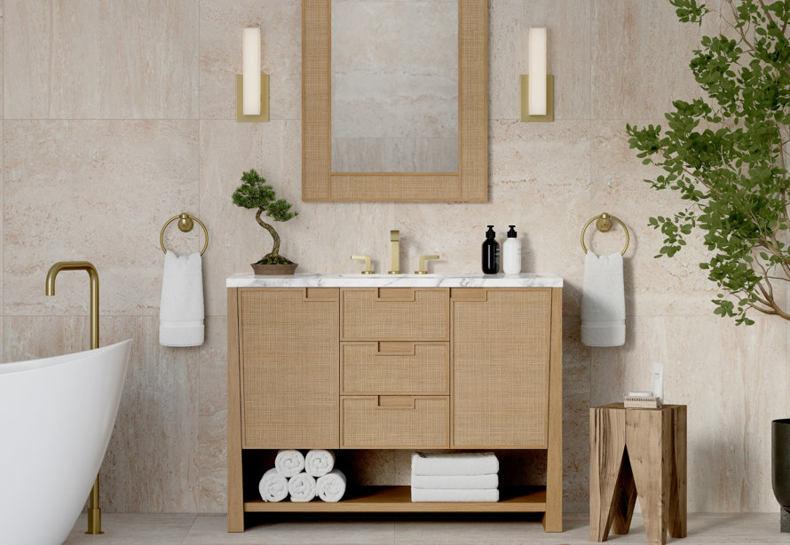 Neutral bathroom with a light wood vanity, brass fixtures, marble top, and stone tile walls.