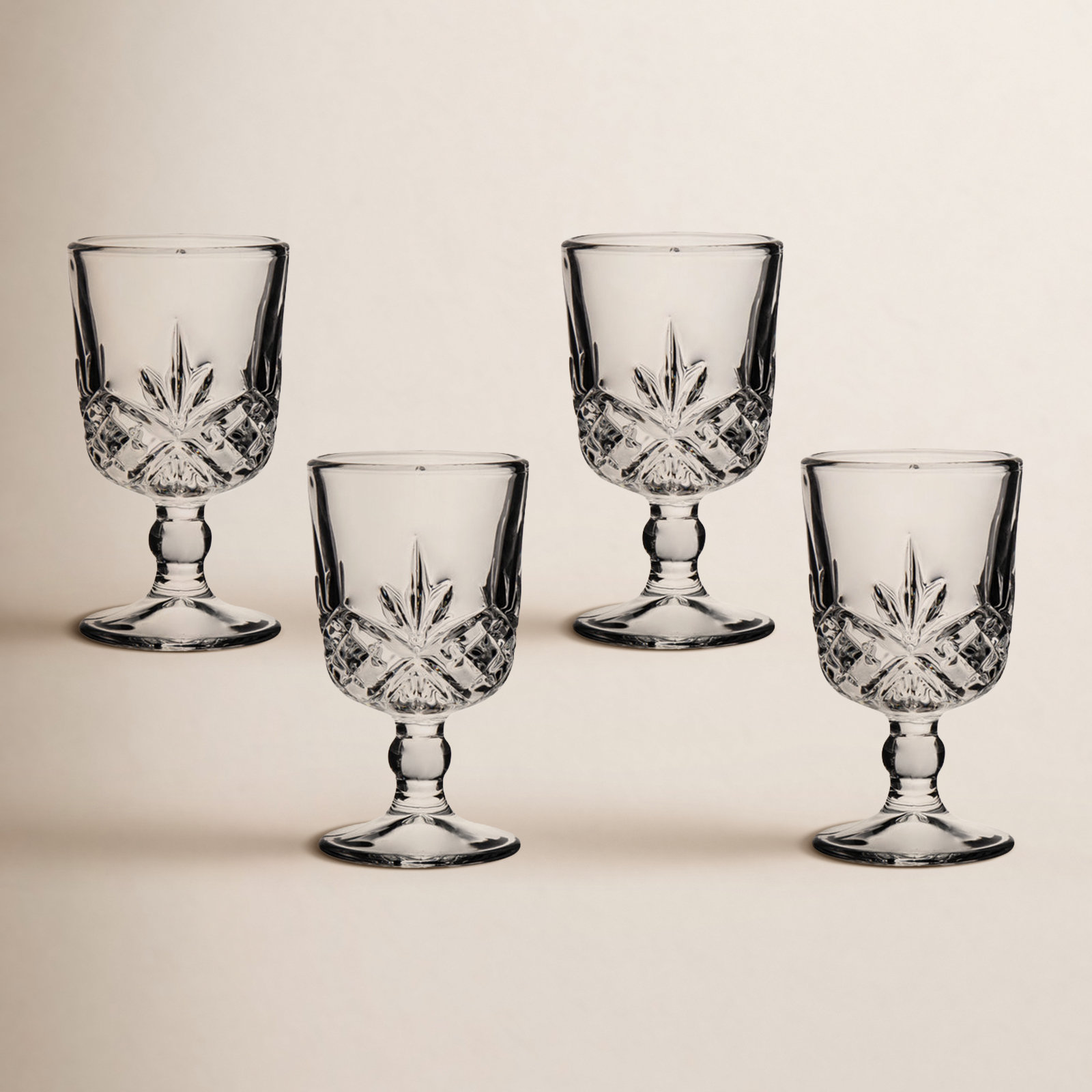 Set of four clear crystal cordial glasses with a starburst pattern and diamond-cut base detail.