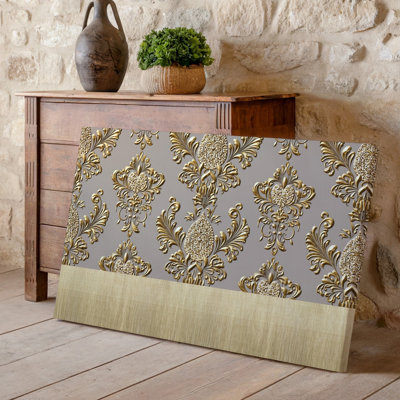 La toile crée un design de papier peint élégant avec un motif damassé complexe en or chatoyant contre un taupe doux