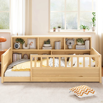 Un lit de plancher en bois simple avec une barrière de sécurité de style clôture, avec une fonction décorative de rangement latérale, et sa couleur est dans le ton de bois naturel.