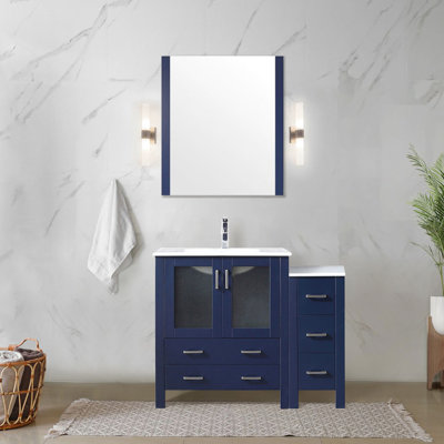 Meuble-lavabo bleu marine de 107 cm de large avec armoire latérale, surface en céramique blanche, miroir aligné de 71 cm, mécanisme de fermeture amortie pour les tiroirs et grand espace de rangement grâce à son grand plan de travail. Nécessite un comptoir anti-taches.