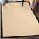 Nannette Handmade Light Beige Berber with Black Faux Leather Border Area Rug