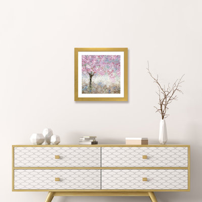 Square cherry blossom tree canvas art in a gold frame mounted on a wall above a wooden dresser