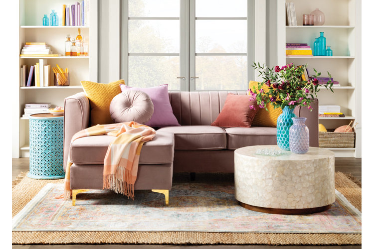 eclectic-style living room with a pink velvet sofa on a vintage-style area rug that’s layered on top of a jute rug