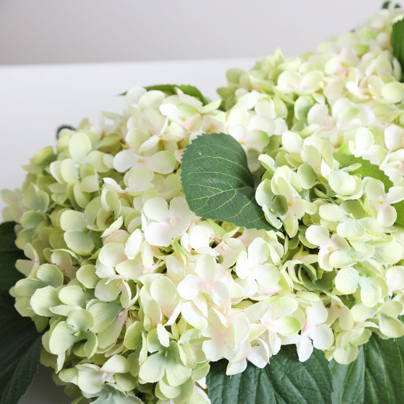 Mélange d'hortensias crème et vert avec centre de table à profil bas dans un bol à pain en bois