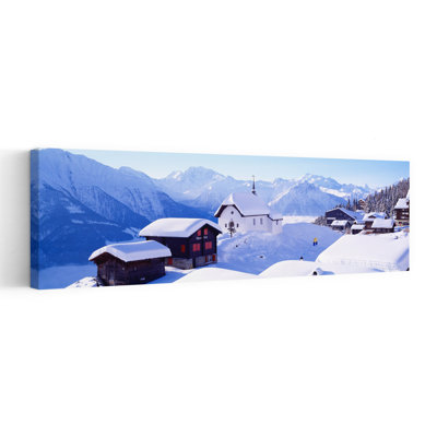 Snow Covered Chapel And Chalets Swiss Alps Switzerland by Bo Brännhage - Wrapped Canvas Panoramic Print