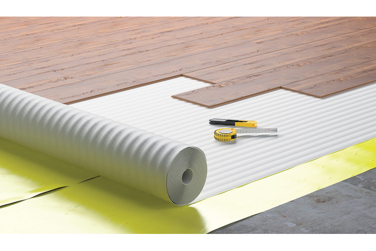 Image showing the layers of subfloor, underlayment, and wood floor panels as they're being installed.