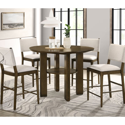 Table de salle à manger ronde brune, hauteur du comptoir, étagère inférieure de rangement, pieds géométriques en planches pour une présentation optimale dans la cuisine, supportée par des éléments angulaires.