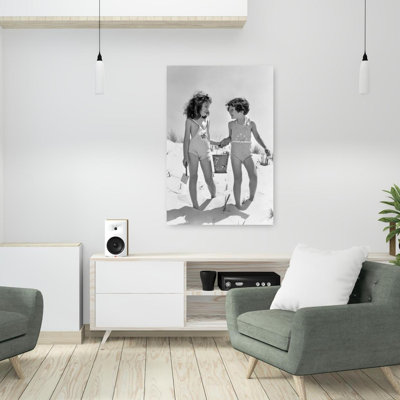 Années 1930, deux filles souriantes, sœurs, amis, tenant par la main, seau à sable et pelle, marchant sur une dune de sable, rétro, rétro, plage, art mural