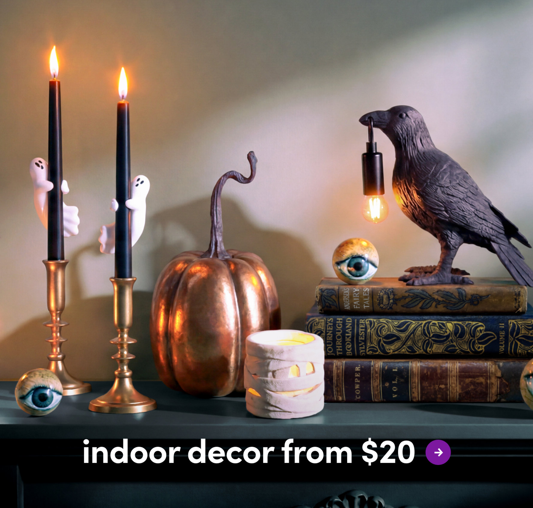 Spooky Halloween-themed console table display featuring a tiered dessert stand, a smoking punch bowl, a Frankenstein bust, and skull accents with the text indoor decor from $20.