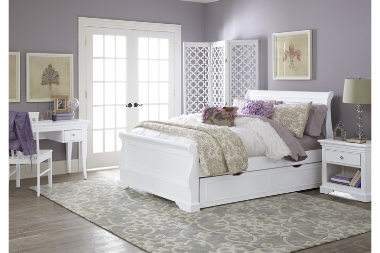 A bedroom with a white bedroom furniture set lavender walls and lavender and neutral bedding