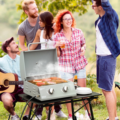 Plateau de table portatif au propane Gris. Pieds pliables pour la mobilité. Pour le camping, le pique-nique, la cour. Couvercle, thermomètre, plateau à graisse. Barbecue au gaz à 2 brûleurs L 21,75 po x l 18,25 po H 16,25 po. Avec pieds.