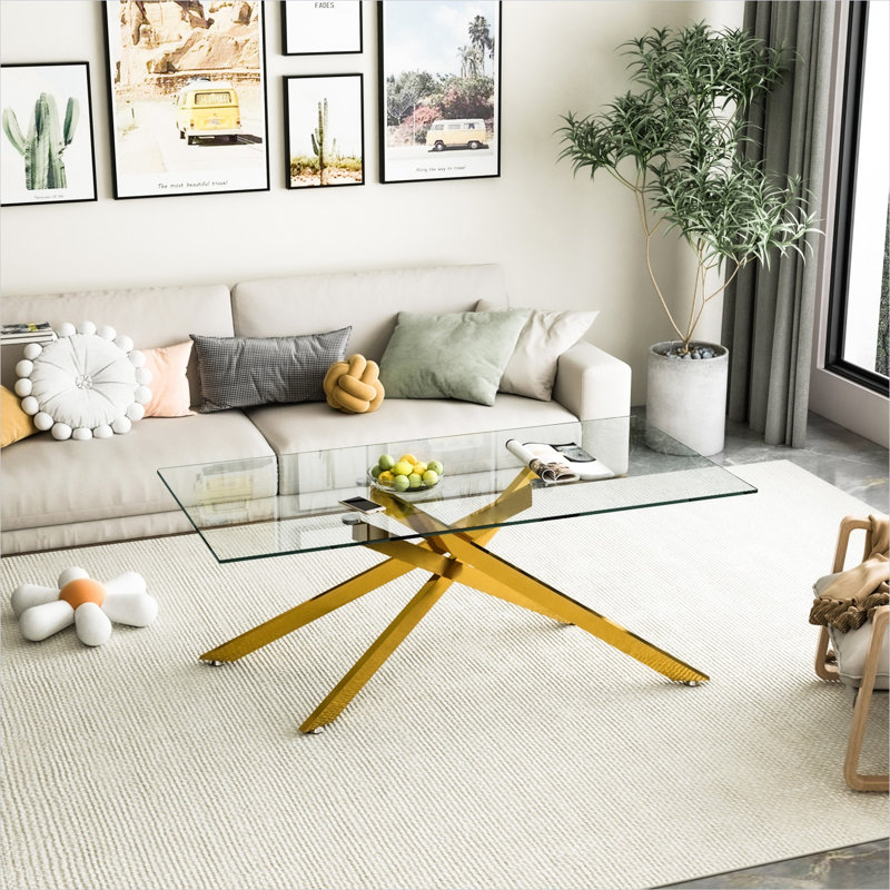 Modern rectangular glass coffee table with clear tempered top and metallic gold legs for living room display