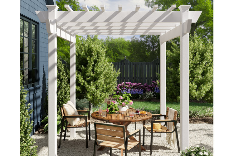 Covered patio idea with a white pergola on a gravel patio with a wood dining table and chair set beneath.